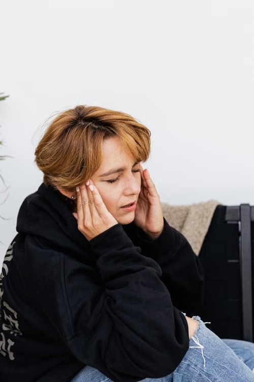 Vrouw met hoofdpijn houdt haar hoofd vast.