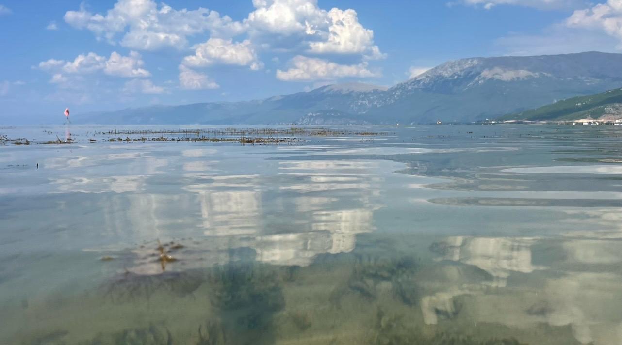 Meer van Ohrid = stilte en weerspiegeling in de natuur Uitzicht over het heldere water van het Meer van Ohrid met weerspiegelende wolken en bergen op de achtergrond
